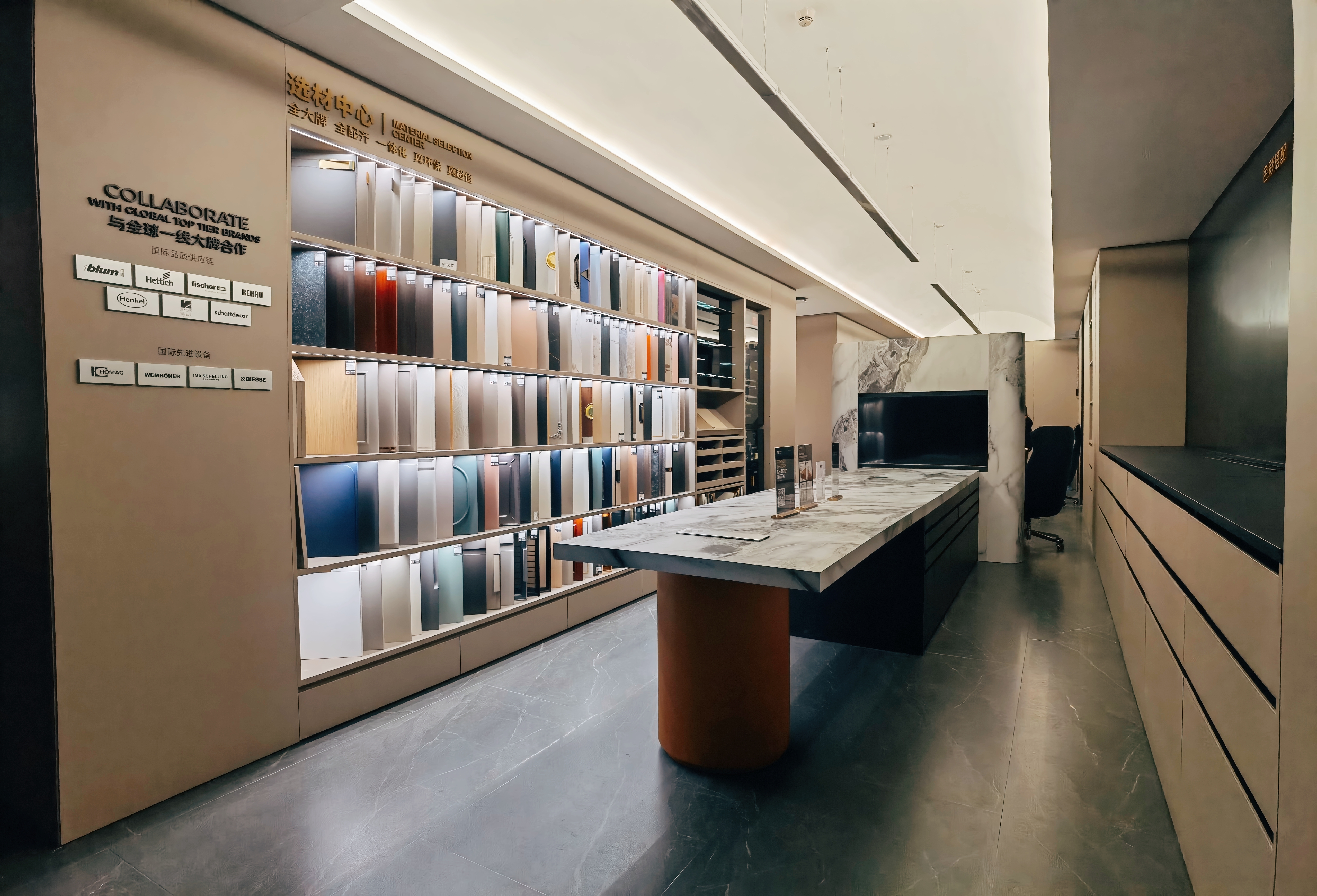 高端家居建材展厅选材中心实景,墙面整齐陈列多色板材样品与木纹饰面,中央摆放岩板台面岛台搭配深色圆柱底座,地面铺设深灰色纹理地砖,整体现代简约风格,展示国际一线品